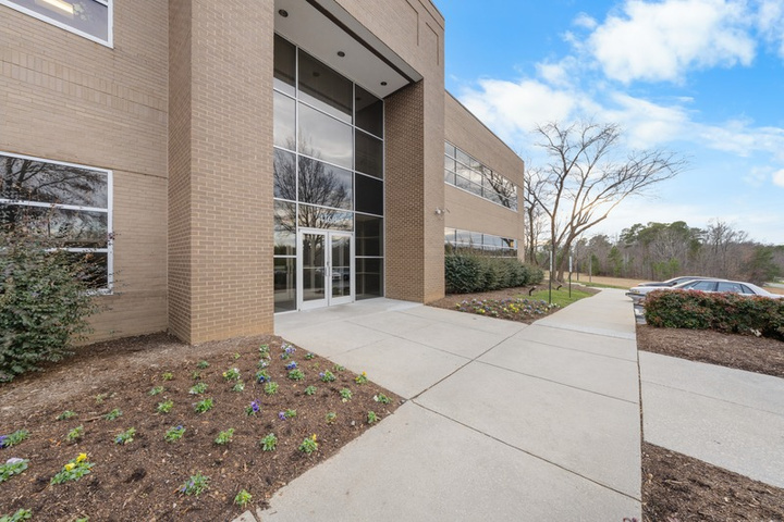 Landscaped sidewalk leading to the building's glass entrance